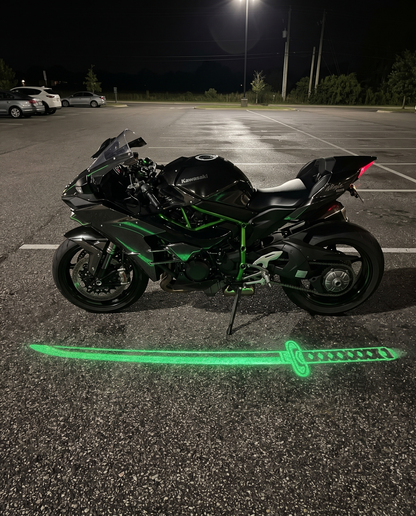 KataGlow green katana light projected on the ground beside a black sportbike at night